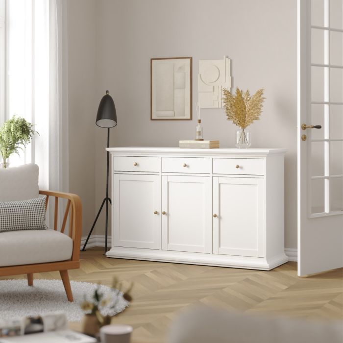 White sideboard in a living room with a lamp and decor items.
