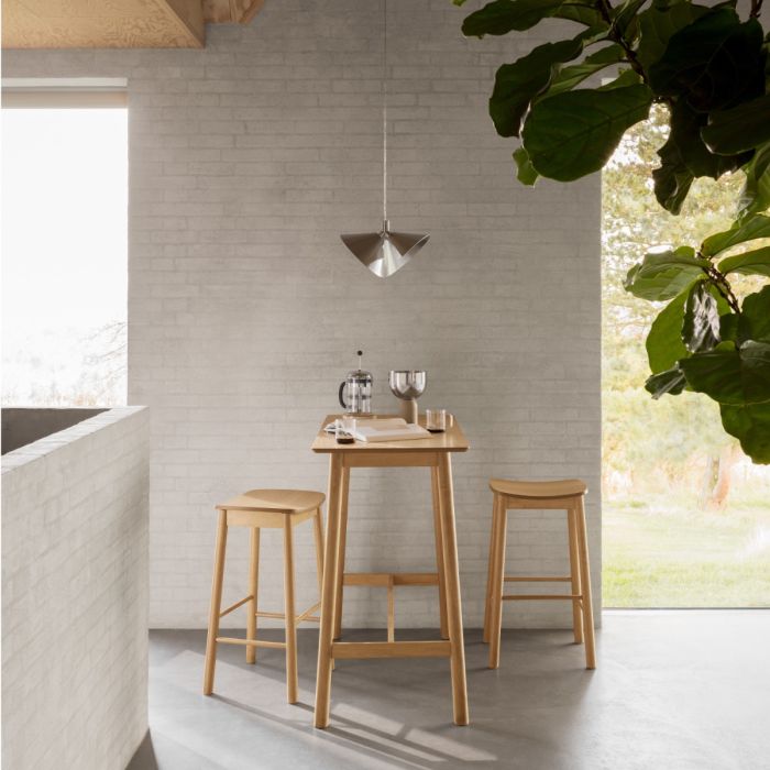 Modern kitchen with wooden bar table and stools against a light gray wall.