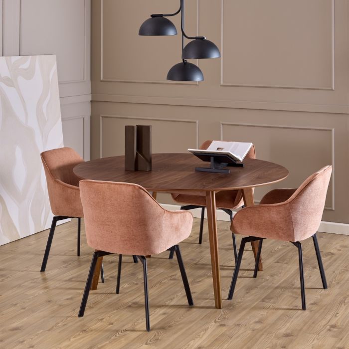 Round wooden dining table with four brown chairs in a room with beige walls and a light wood floor.