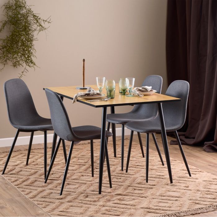 Dining table set with four gray chairs on a textured rug.