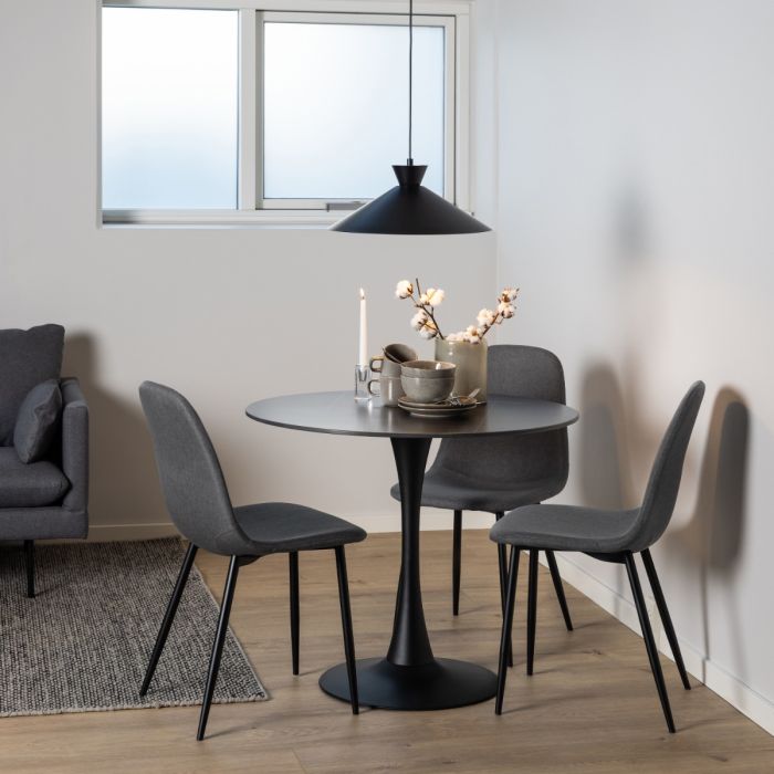Dining area with a round black table and gray chairs in a room with a window.