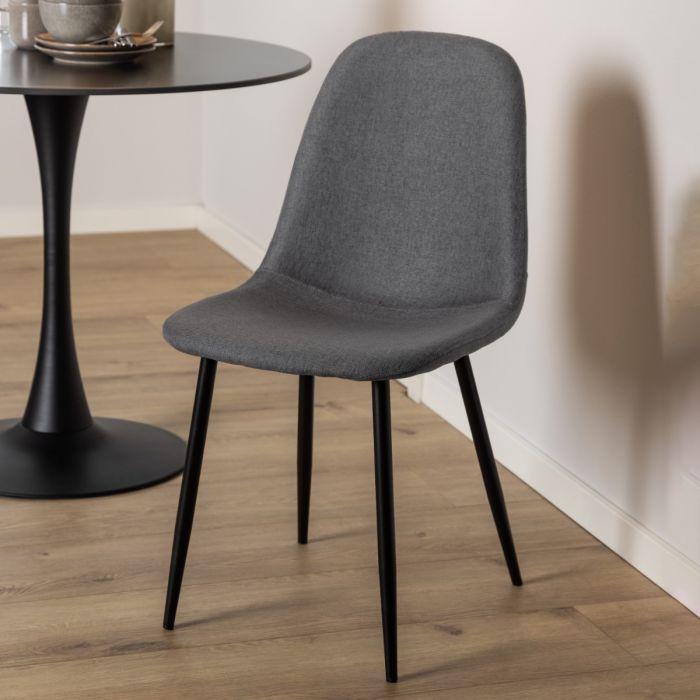Gray chair with black legs on a wooden floor next to a black table.