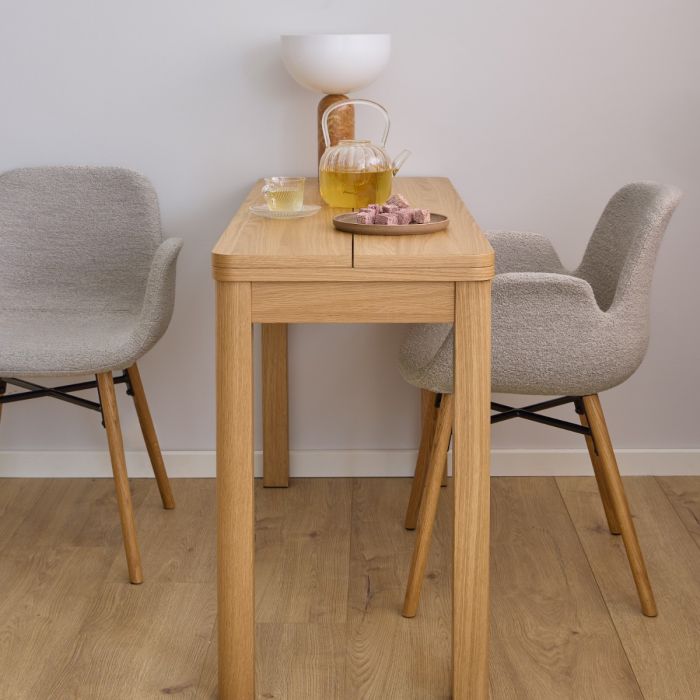 Wooden dining table with two gray chairs in a room with a light gray wall.