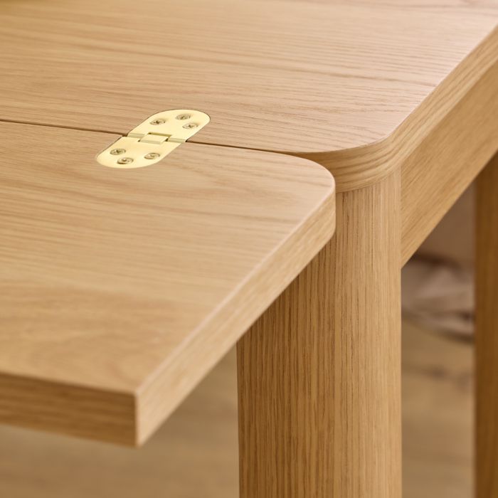 Close-up of a wooden table corner with a visible hinge.