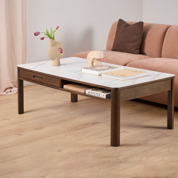 Coffee table with books and a vase on it, placed in front of a sofa.