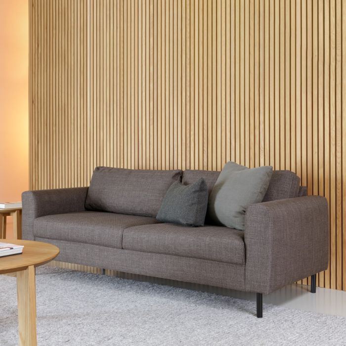 Gray sofa with cushions against a wooden paneled wall.