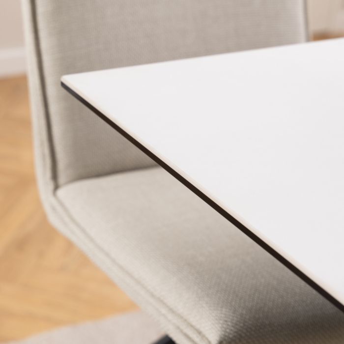 Close-up of a beige chair with a white cushion on a wooden floor.