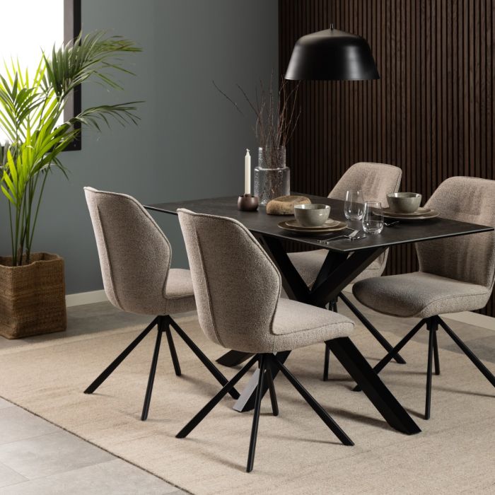 Dining room with a black table and beige chairs, featuring a plant and lamp.