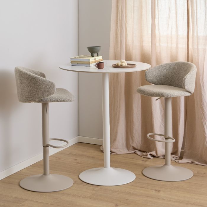 Two beige bar stools with white bases in front of a small round table in a room with pink curtains.