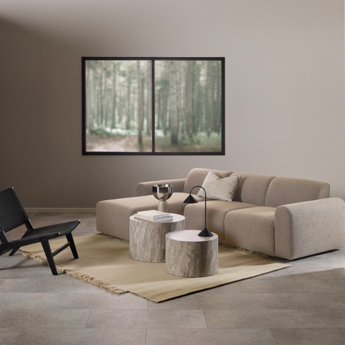 Modern living room with beige sectional sofa, black chair, and abstract art on wall.