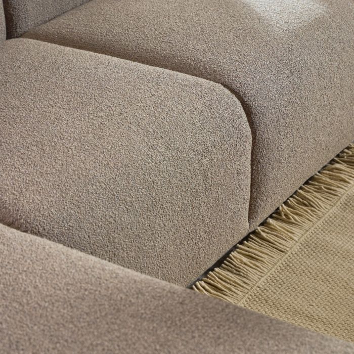Close-up of a textured beige fabric surface with a fringed edge.