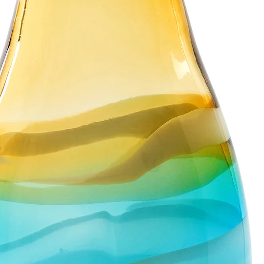 Close-up of a glass vase with yellow and blue layers on a white background