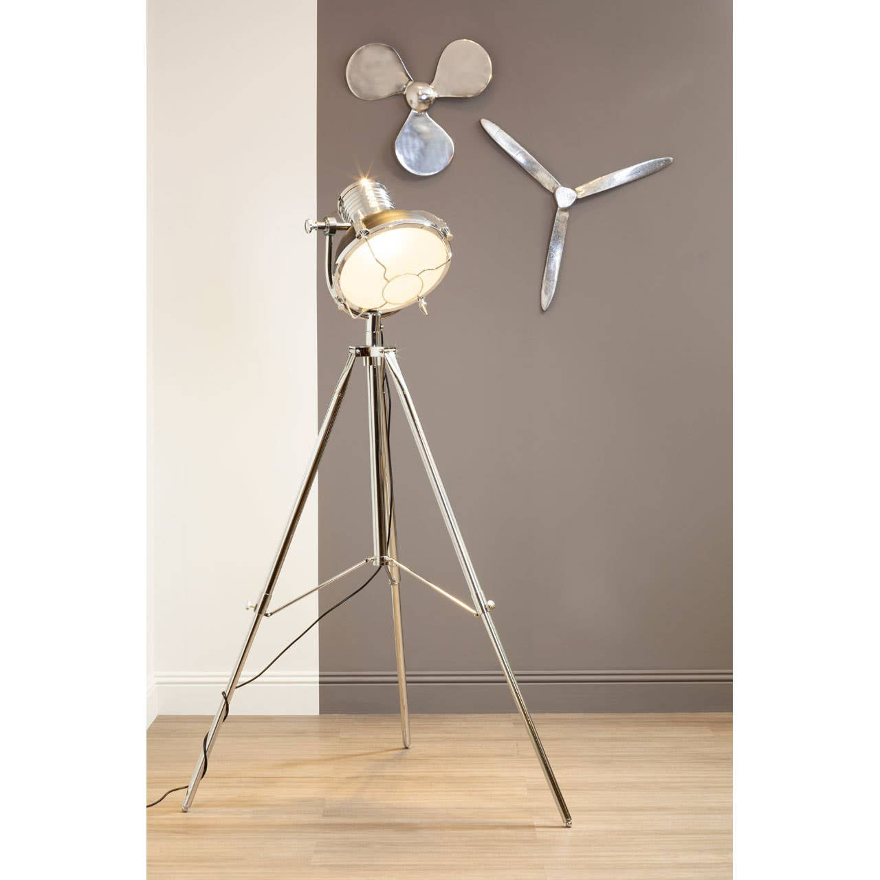 Floor lamp with propeller design on a wooden floor against a gray wall.