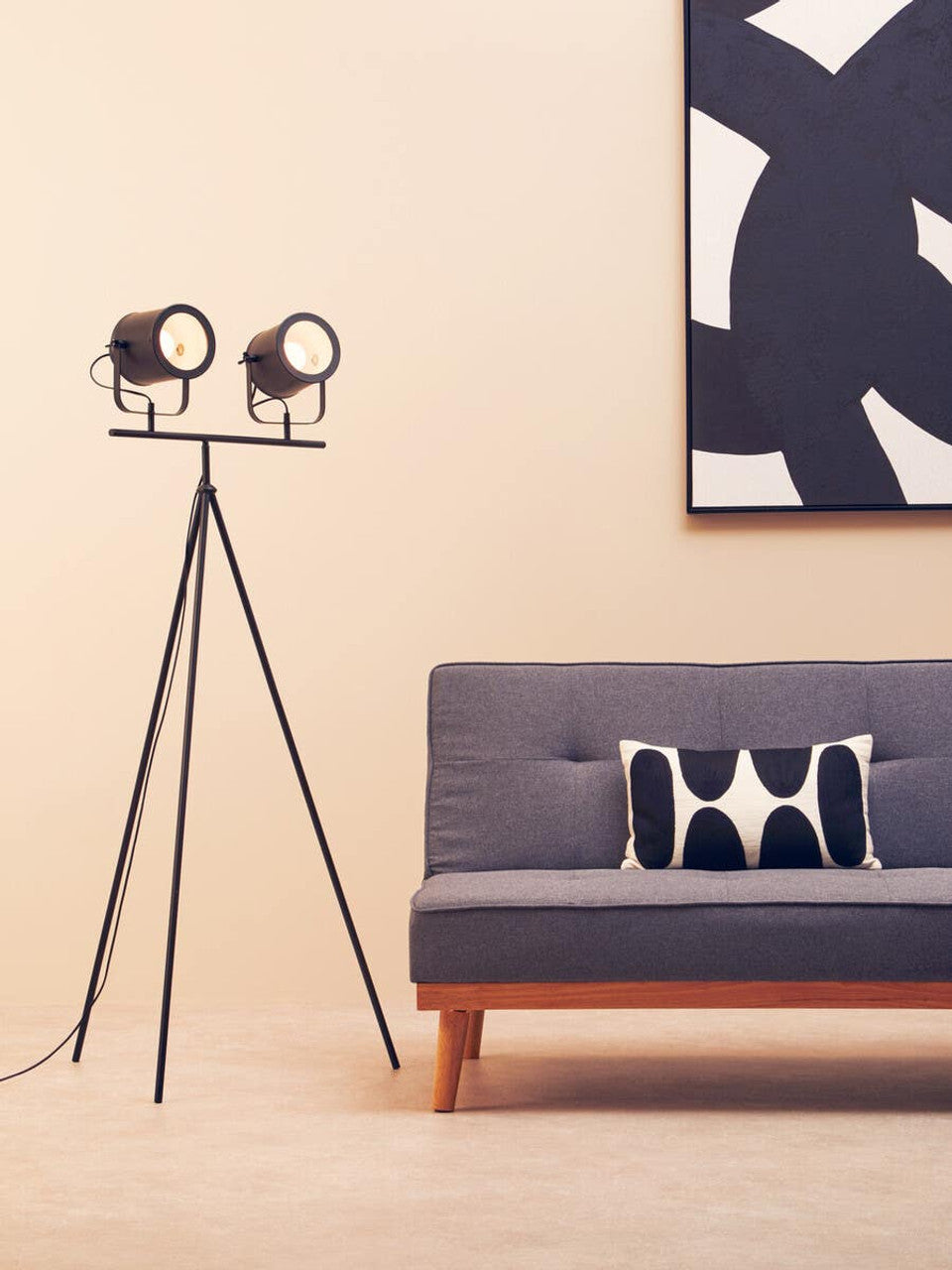 Modern living room with a gray sofa, decorative pillow, and a tripod floor lamp.