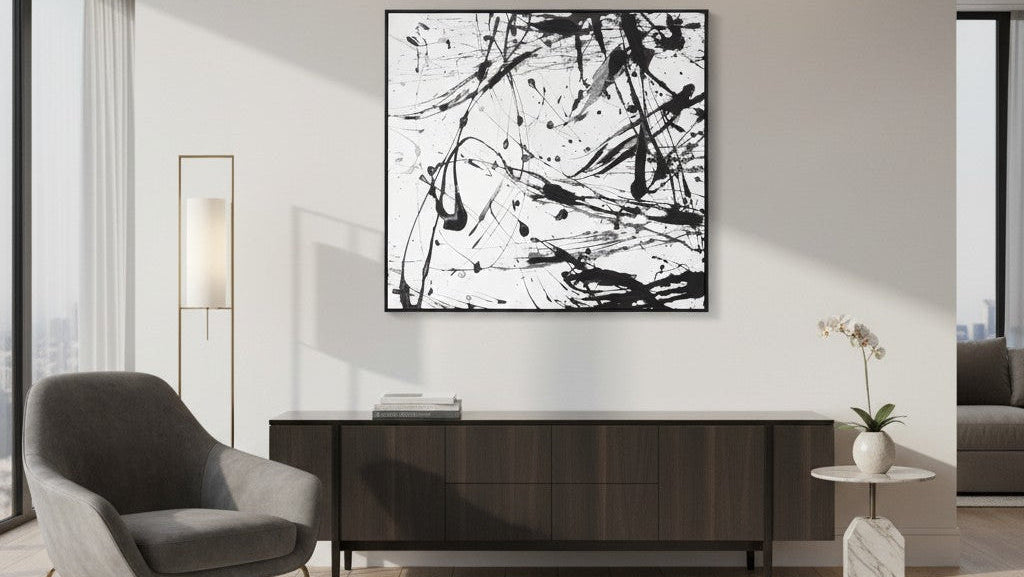 Modern interior with abstract black and white painting on a wall, gray armchair, and wooden console table.