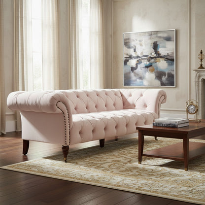 Pink tufted sofa in a living room with a coffee table and artwork on the wall.