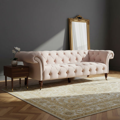 Pink tufted sofa in a room with a mirror and small table.