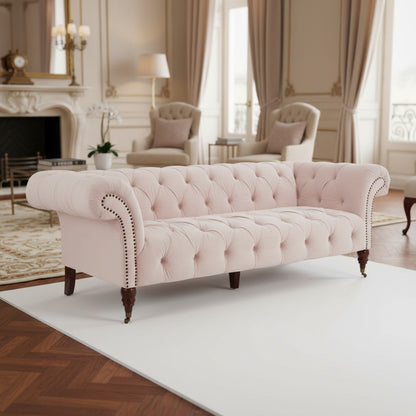 Pink tufted sofa in a elegant living room setting with curtains and fireplace.