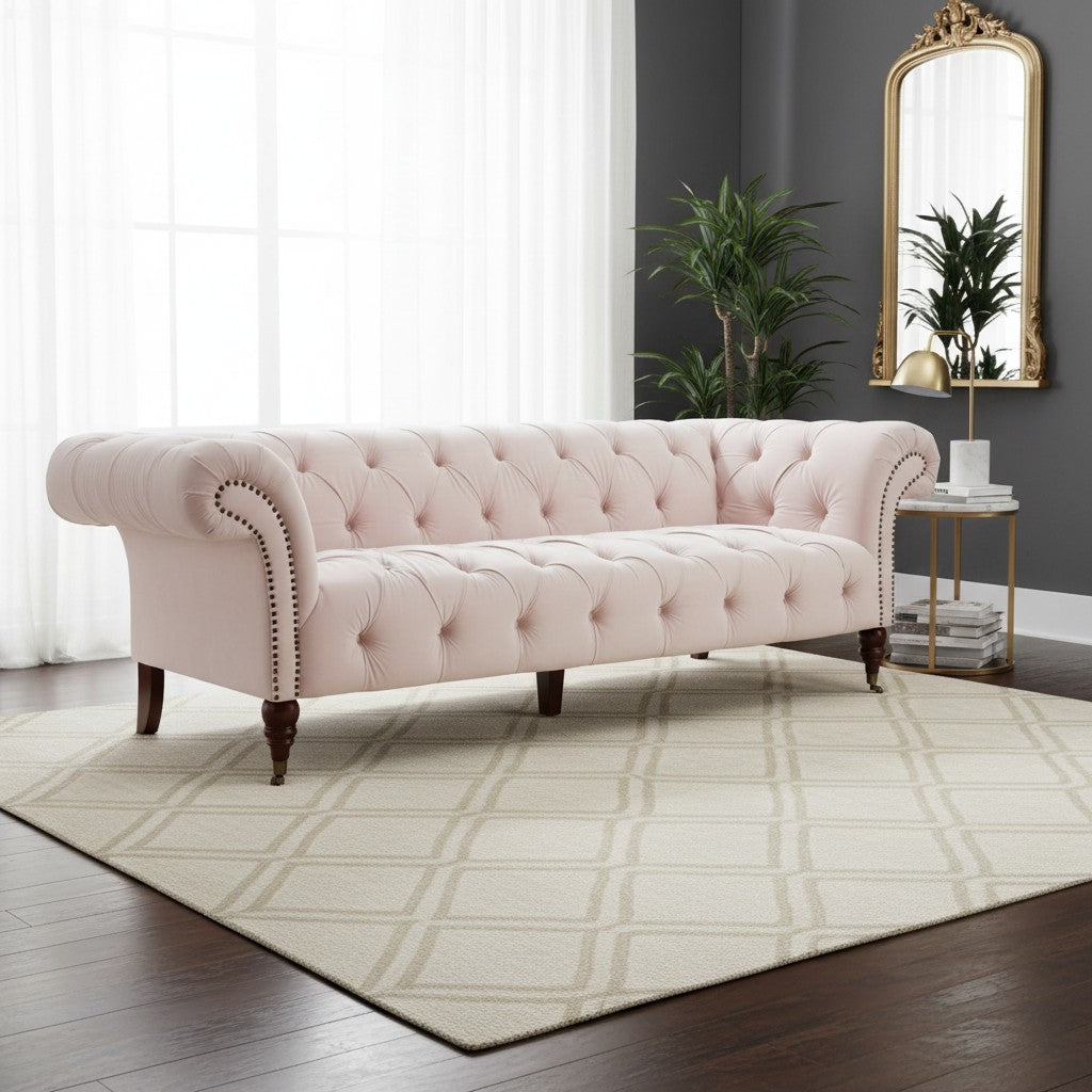 Pink tufted sofa in a living room with a mirror and plants.