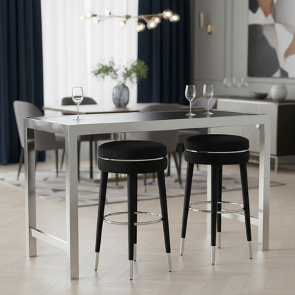 Modern dining area with a stainless steel table and black bar stools in a stylish interior.