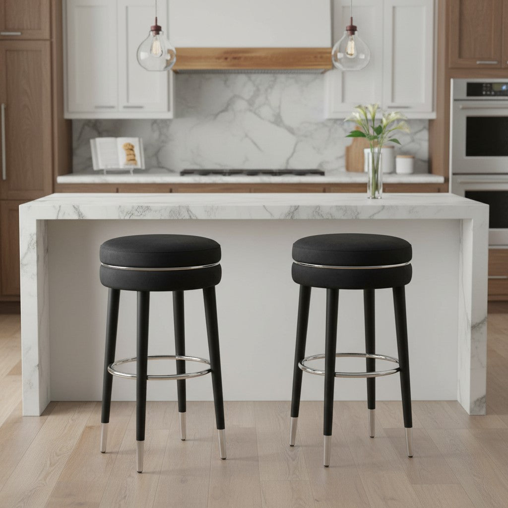Two black bar stools in front of a kitchen island with marble countertop.