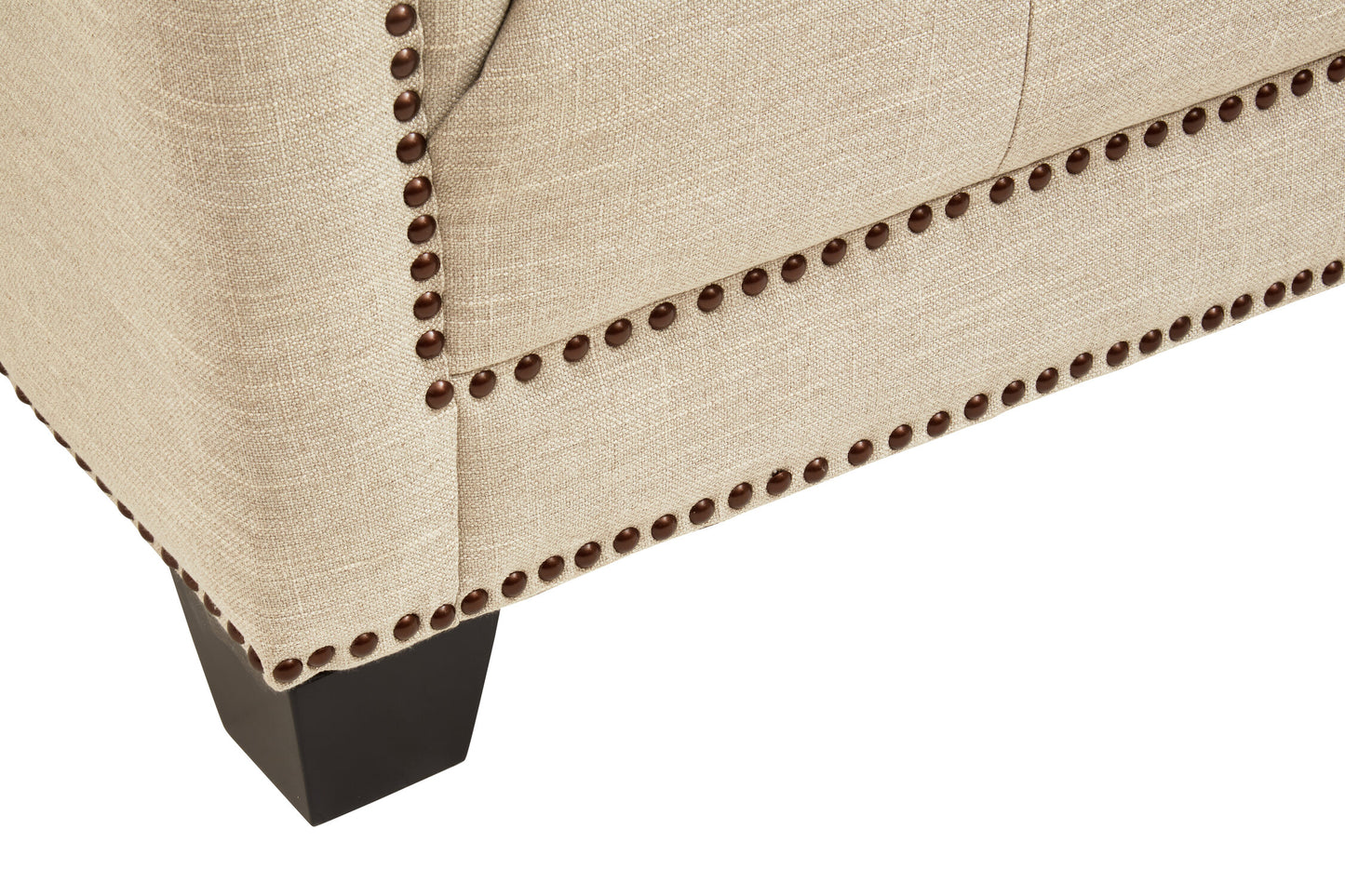 Close-up of a beige upholstered chair with nailhead trim on a white background