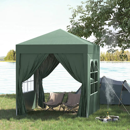 Green outdoor canopy tent with curtains and chairs near a body of water.