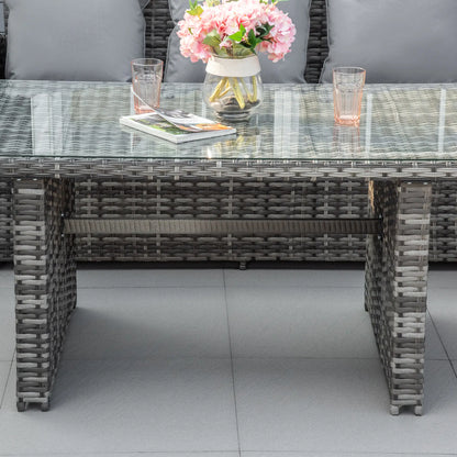 Outdoor table with wicker design, glass top, and decorative items on a patio.