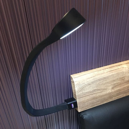 Black flexible desk lamp attached to a wooden block with a purple textured background