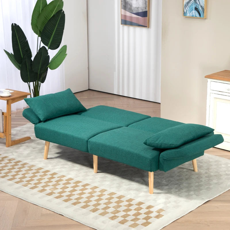 Green sofa bed in a room with a plant and side table.