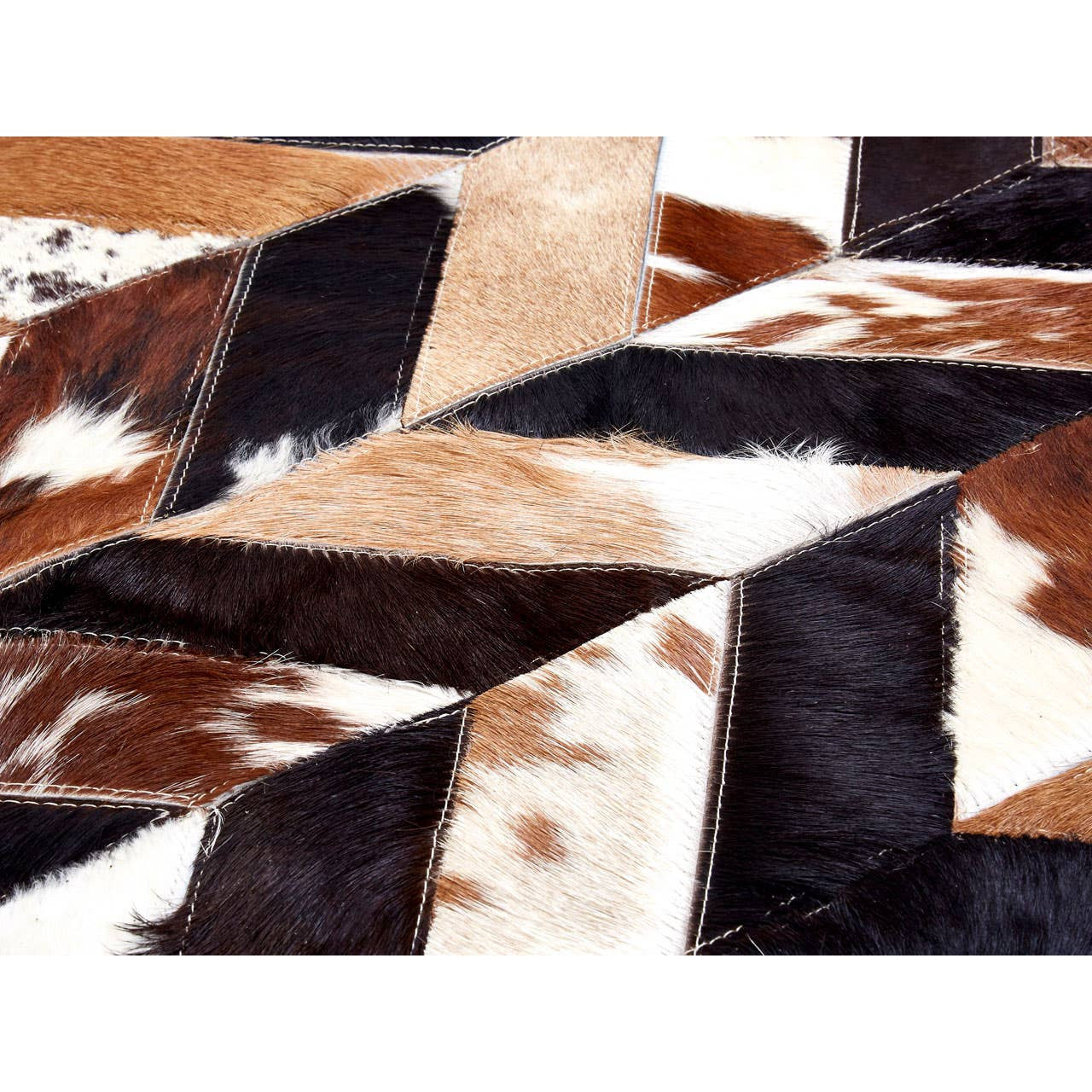 Geometric patterned cowhide rug with brown, black, and white patches.