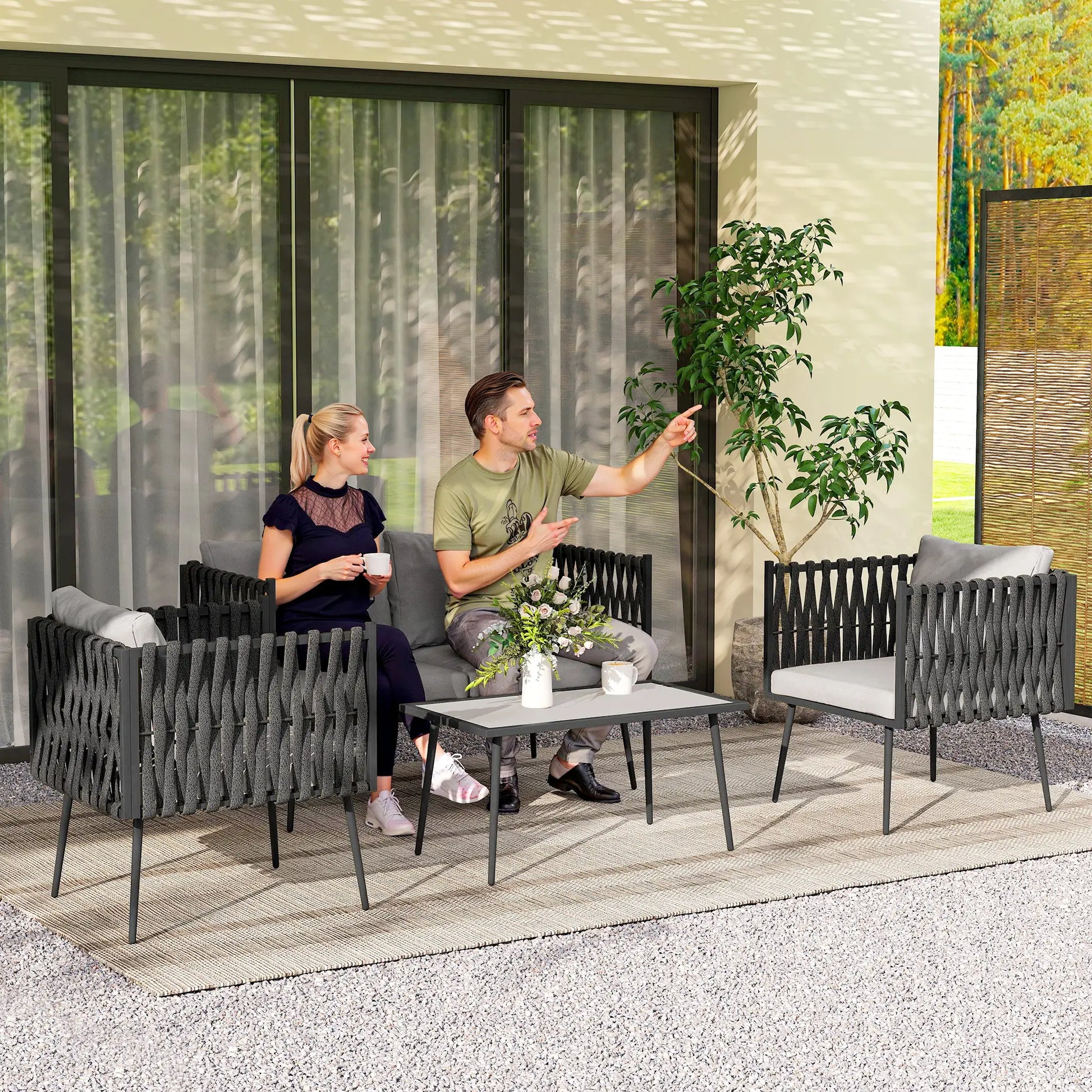 Two people sitting on outdoor furniture set with a table and plants.