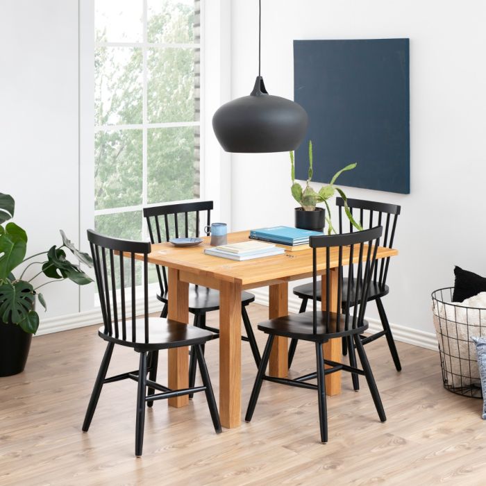 Dining room with wooden table and black chairs near a window.