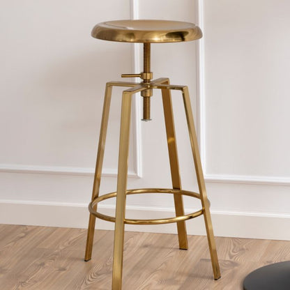 Gold metal bar stool on a wooden floor with a white wall background
