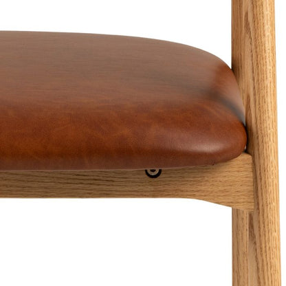 Close-up of a brown leather seat on a wooden chair with a white background