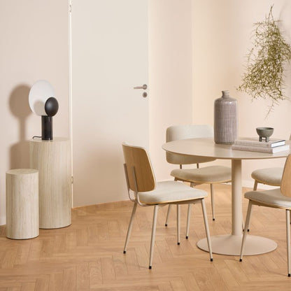 Modern dining room with a round table and chairs on a wooden floor.