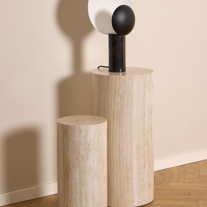Two cylindrical marble side tables against a beige wall.