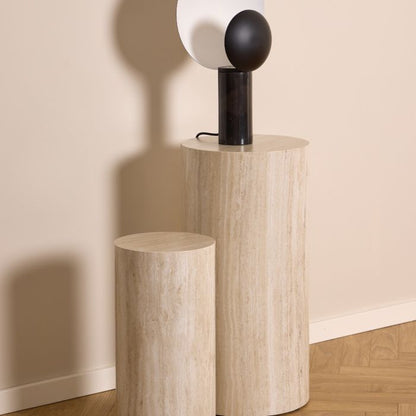 Two cylindrical marble side tables against a beige wall.