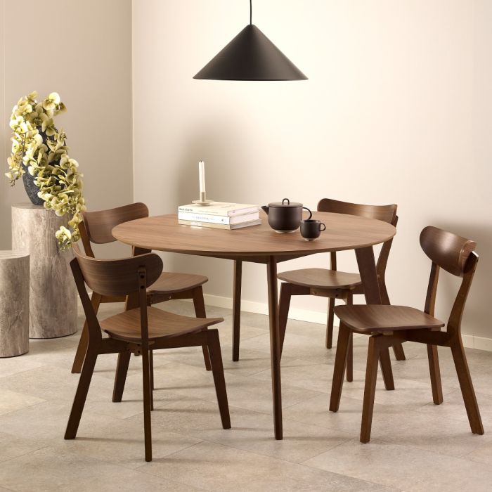 Dining room with wooden table and chairs, books, and a teapot.