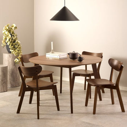 Dining room with wooden table and chairs, books, and a teapot.