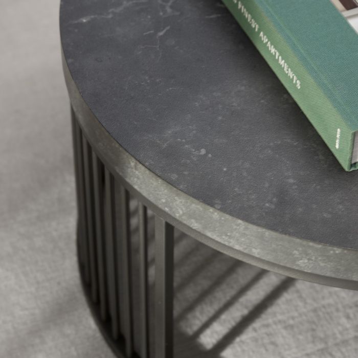 Round black table with a green book on a gray surface