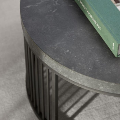 Round black table with a green book on a gray surface
