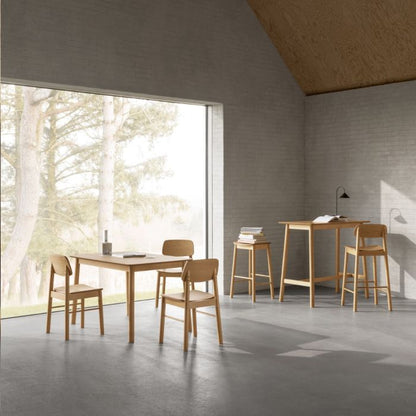 Modern dining area with wooden tables and chairs in a room with large windows.