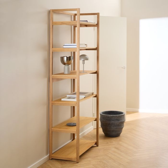 Tall wooden bookshelf with decorative items against a beige wall.
