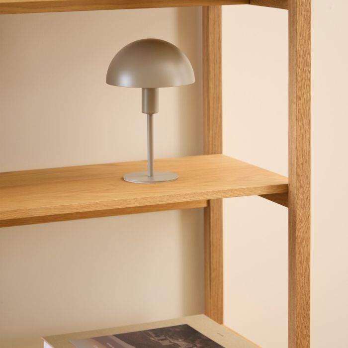Silver table lamp on a wooden shelf against a beige wall