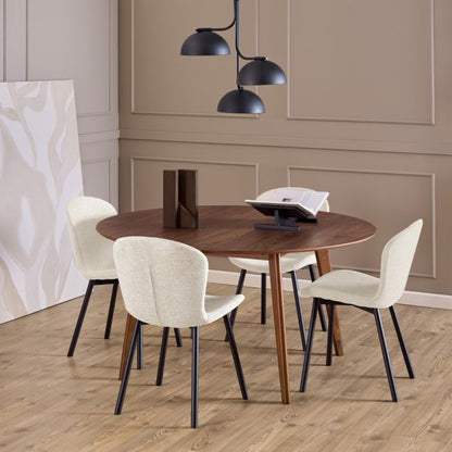 Dining area with a wooden table and white chairs in a room with beige walls and wooden flooring.