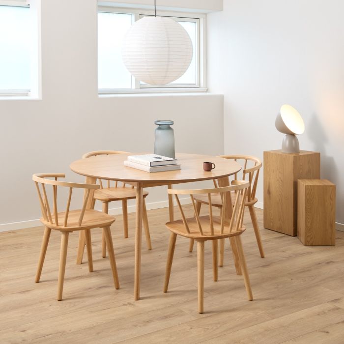 Dining area with wooden table and chairs in a room with light-colored walls and flooring.