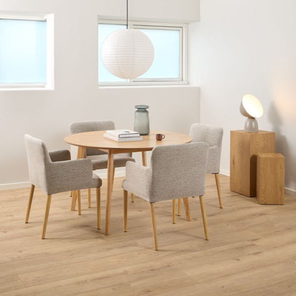 Dining area with round wooden table and four gray chairs in a bright room.