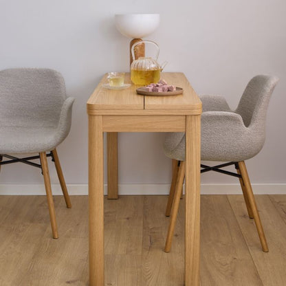 Wooden dining table with two gray chairs in a room with a light gray wall.