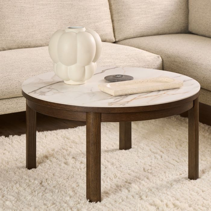 Round coffee table with marble top and wooden base in front of a beige sofa.